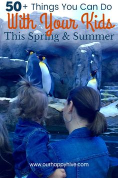 a woman and her child looking at penguins in an aquarium with text overlay that reads 50 things you can do with your kids this spring & summer