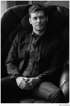 a man sitting in a chair wearing a suit and tie