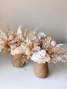 two vases filled with dried flowers and feathers