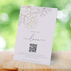 there is a card that has been placed on a wooden table with flowers in the background