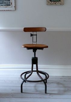 an old fashioned stool sits in front of two pictures on the wall