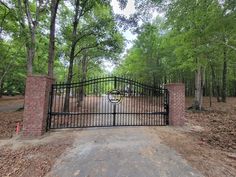 an iron gate in the middle of a wooded area