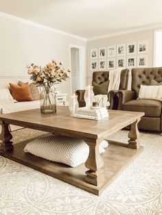 a living room with two couches, a coffee table and a vase filled with flowers