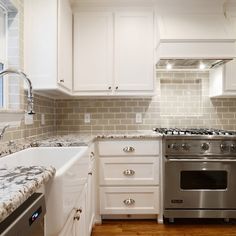 a kitchen with white cabinets and marble counter tops, stainless steel appliances and an oven