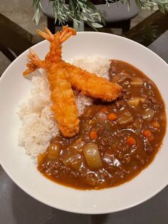 a white plate topped with rice and meat covered in gravy on top of a table