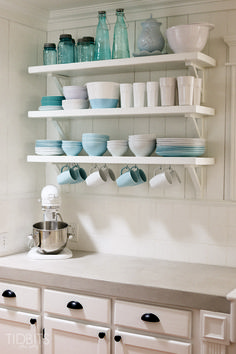 a kitchen with white cabinets and shelves filled with blue glassware on top of them