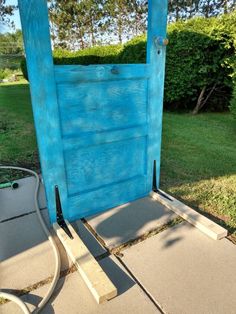 a blue wooden door sitting in the middle of a sidewalk next to a grass field