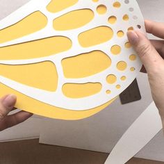 someone is cutting out some paper to make something yellow and white that looks like a flower