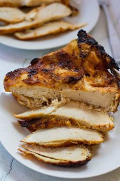 two white plates with slices of chicken on them