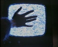 a person's hand on top of a television with the screen lit up blue