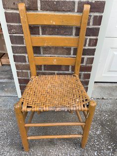 an old wooden chair sitting in front of a brick wall