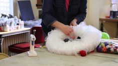 a woman in a black shirt and red tie is making a fluffy white object with yarn