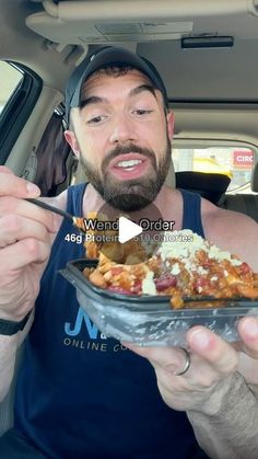 a man in the back seat of a car holding a plate of food with a fork and knife