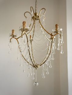 a chandelier hanging from the ceiling in a room with white walls and flooring