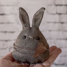 a hand holding a small stuffed animal with string wrapped around it's face and eyes