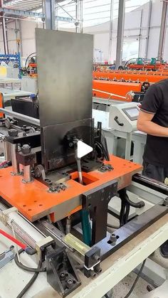 a man standing in front of an assembly line working on something with machinery behind him