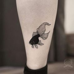 a black and white photo of a goldfish tattoo on the leg