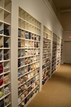 a room filled with lots of white shelves covered in different types of folded shirts and ties