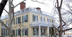 a large yellow house with green shutters and white balconies on the second story