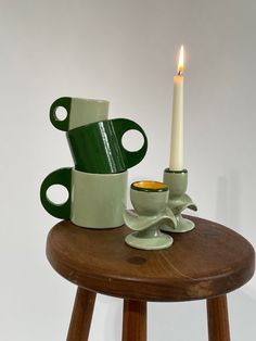 a table with two cups and a candle on it, sitting next to each other