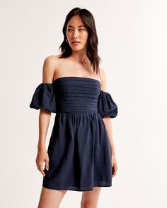 Flattering short-sleeve mini dress in a textured flowy fabric, featuring off-the-shoulder puff sleeves, ruching details along the bodice and waist and center-back smocking for the perfect fit. Recruitment Dresses, Indigo Dress, Flowy Fabric, American Clothing, Short Sleeve Mini Dress, Beauty Clothes, Dark Indigo, New Arrival Dress, Mini Dress With Sleeves