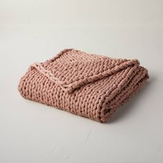 a pink knitted blanket on a white surface