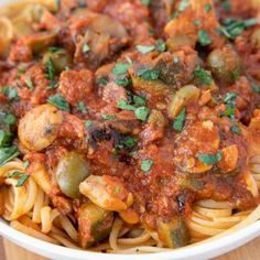 a bowl filled with pasta covered in sauce and vegetables