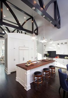 a large kitchen with white cabinets and wooden counter tops, along with bar stools