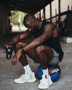 a man sitting on top of a blue ball holding a water bottle in his hand