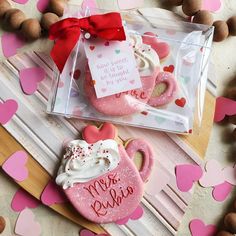 two decorated cookies in the shape of teapots on a table with hearts and confetti