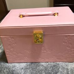 a pink box sitting on top of a bed next to a wooden table with a gold handle