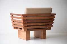 a chair made out of wooden planks on top of a white floor with a beige cushion