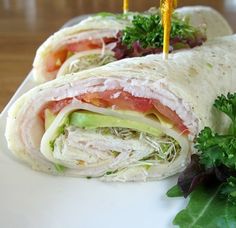 a close up of a burrito on a plate with lettuce and tomatoes