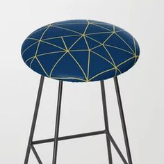 a blue stool with yellow lines on the top and bottom, sitting in front of a white wall