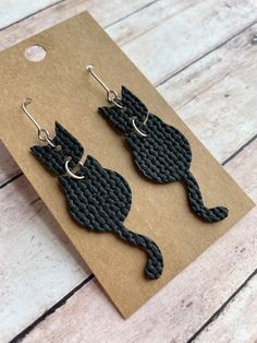 The cutest cat earrings! Made with stainless steel earring findings and faux leather (single-sided).  Each pair of earrings will be slightly different because of the variability in the faux leather pattern.  2.625 inches long by .625 inches wide. Free shipping on orders $35 and over! Warning: Choking Hazard. Small Parts. Keep out of reach of children under 5 years old. Faux Leather Knot Earrings Diy, Leather Ear Rings Diy, Homemade Leather Earrings, Leather Cricut Earrings, Faux Leather Halloween Earrings, Faux Earring Ideas, Halloween Leather Earrings, Halloween Faux Leather Earrings, Faux Leather Earring Ideas