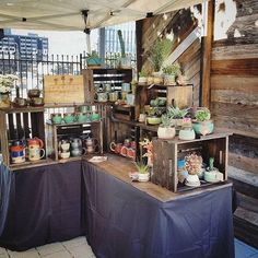 an outdoor market with potted plants and other items for sale on the outside tables