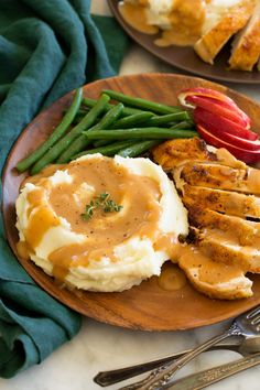 a plate topped with mashed potatoes, green beans and chicken breast covered in gravy