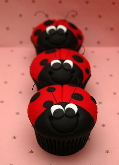 three cupcakes decorated like ladybugs sitting on top of a table