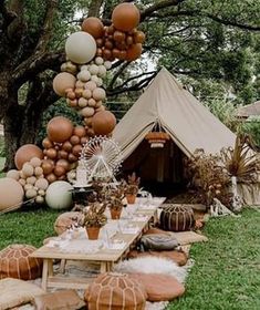 an outdoor tent set up for a party with balloons and other decorations on the grass