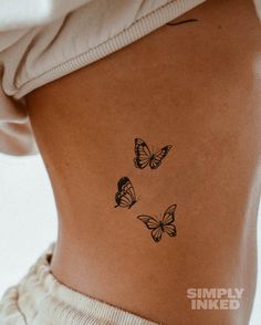 the back of a woman's stomach with three butterflies tattooed on her lower body