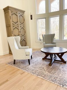 a living room with two chairs and a coffee table in front of a large window