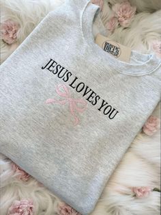 a t - shirt with the words jesus loves you on it and pink flowers in the background