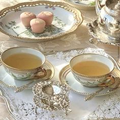 two teacups and saucers on a table with lace doily around them