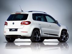 the rear end of a white vw tigua parked in front of a gray background