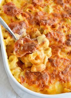 a casserole dish filled with macaroni and cheese, topped with meat