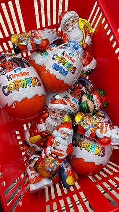 a red shopping basket filled with lots of candies next to santa clause stuffed eggs