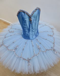 a blue ballerina tutule sitting on top of a wooden floor