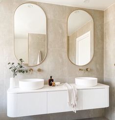 two round mirrors are above the sinks in this bathroom