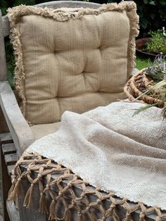 a chair with a blanket on it and some plants in the back ground next to it