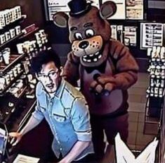 a man standing next to a giant teddy bear in a store